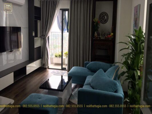 Phòng khách gọn gàng với bộ sofa nỉ êm ái, bàn thờ đứng nhỏ tinh tế và hệ kệ tivi liền tủ trang trí làm từ gỗ công nghiệp bền bỉ