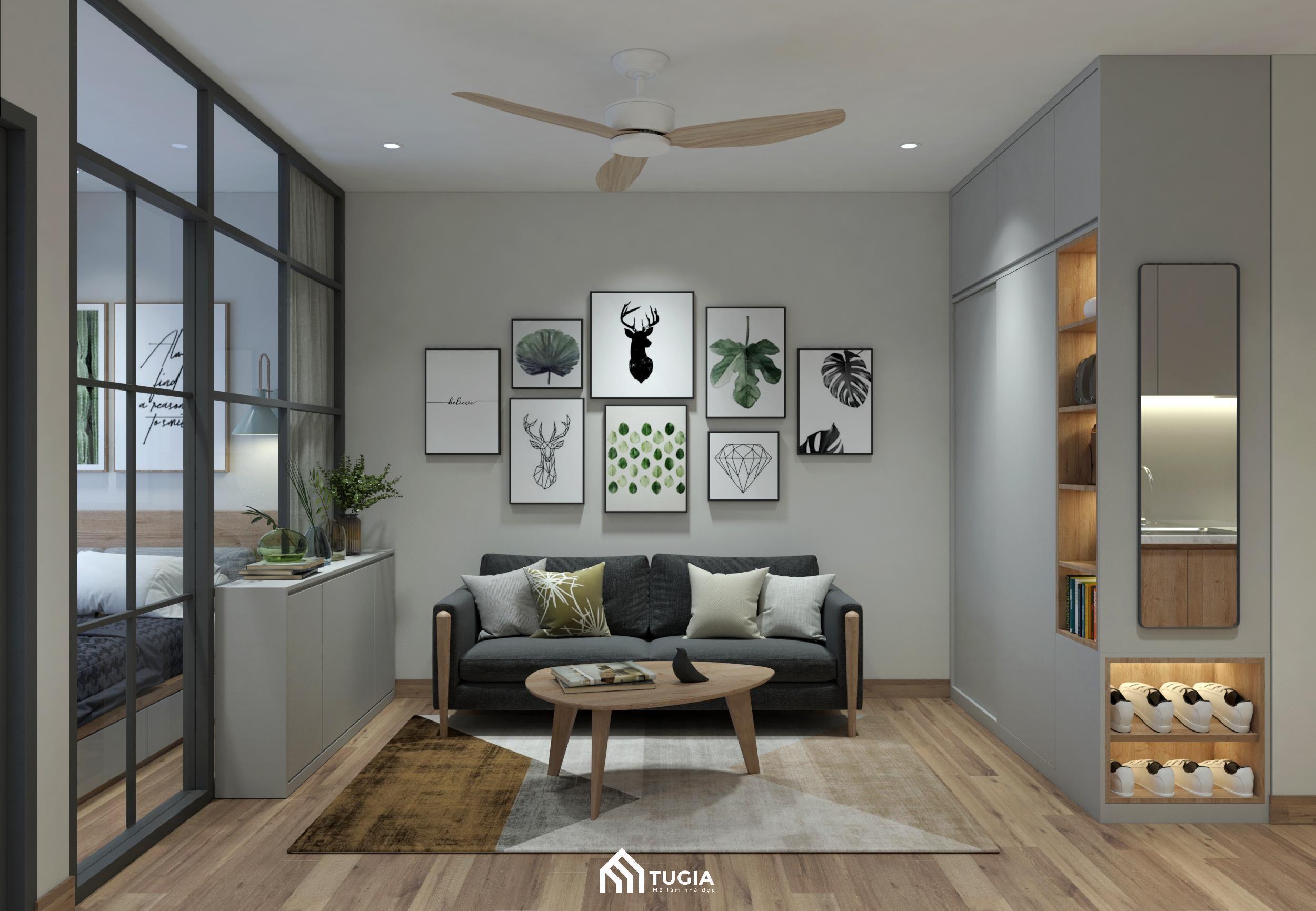 Khu vực phòng khách nổi bật với sofa tối màu, bàn trà gỗ tròn nhỏ gọn, kệ trang trí đơn giản cùng những bức tranh nghệ thuật treo tường tạo điểm nhấn