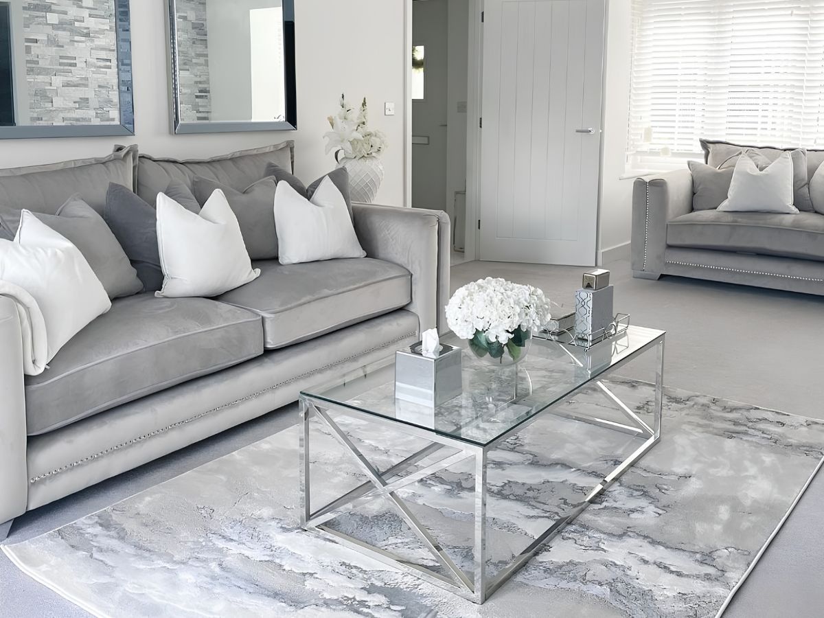 Phòng khách màu xám trắng thanh lịch với sofa bọc nhung và bàn trà kính chân inox