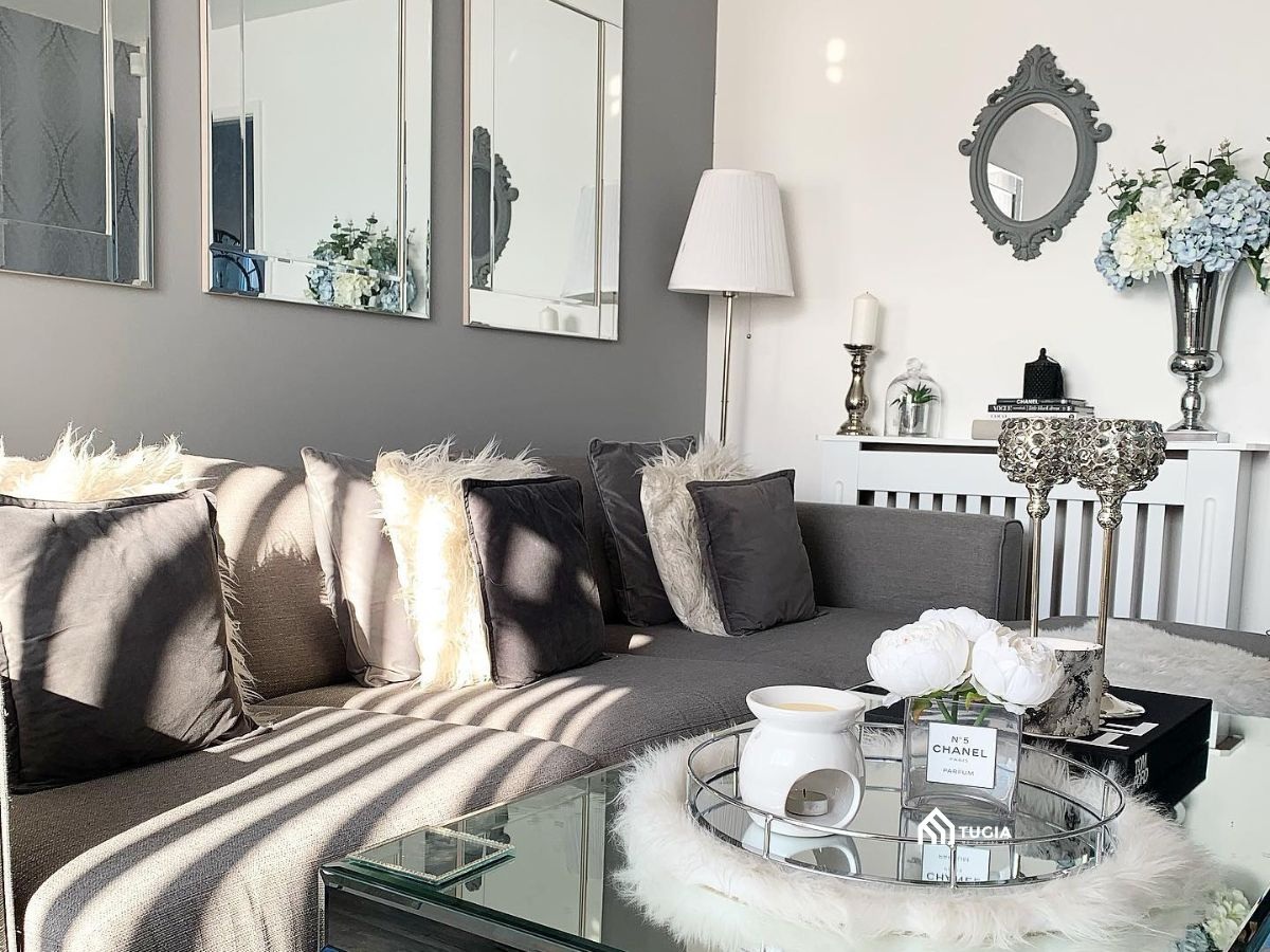 Trang trí phòng khách màu xám trắng với sofa nỉ và bàn trà mặt gương phản chiếu ánh sáng